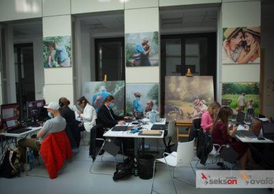 Organizatorzy konferencji przy biurkach, pracują przy laptopach. W tle na ścianie wiszą prace fotograficzne projektu Pełnosprawni w miłości.